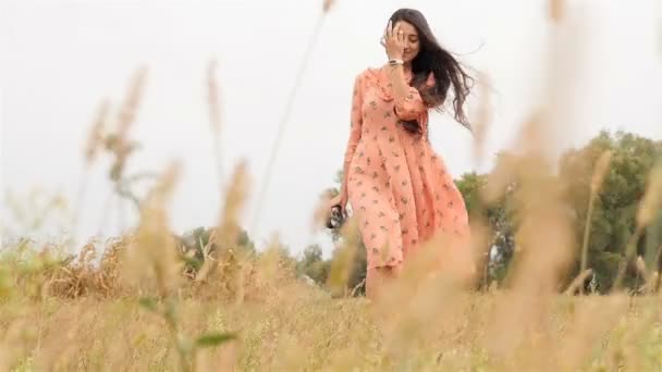 Una chica con una cámara está en el campo. Bonita sonrisa. Movimiento lento — Vídeos de Stock