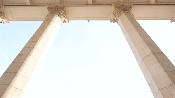 The girl looks at the high columns. Blue sky. Slow motion — Stock Video