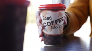 Kahveli kağıt bardak. Yakın plan. Kadın eli işte. Yavaş çekim