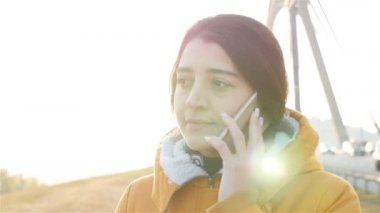 Kız, telefonda konuşuyordu. Güzel esmer. Yolun kenarındaki caddede. Ağır çekim. HD. Kiev, Ukrayna 10.24.2018