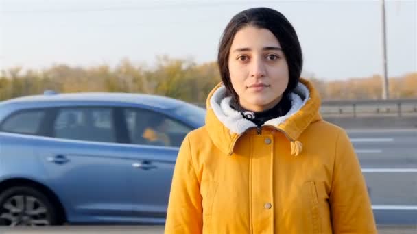 The girl is looking at the camera. Passing cars. Timelapse — Αρχείο Βίντεο