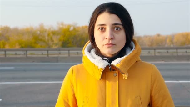 The girl looks frightened at the camera. Slow motion. Close-up. Passing cars — Wideo stockowe