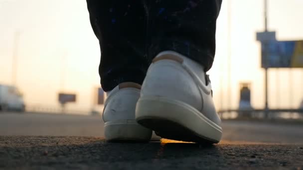 Human legs on a sunset background. City bridge. The movement of cars. Slow motion. Close-up. Sunlight on the pavement — Stock Video