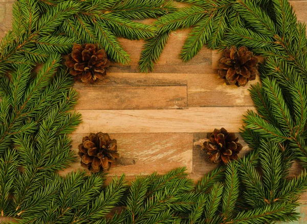 クリスマスの背景 スプルースの枝およびコピーのためのスペースを持つ木製の表面円錐形 — ストック写真
