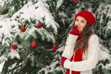 Noel ve yeni yıl kavramı. Kış vibes. Neşeli Noel ağacı yakınındaki eldiven ve kırmızı şapkalı kız. Uzay kopyalayın. portre