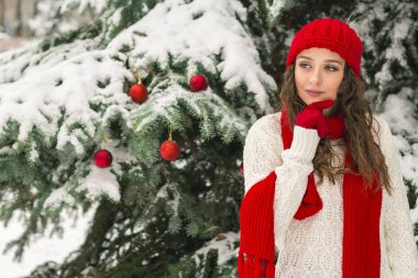 Noel ve yeni yıl kavramı. Kış vibes. Neşeli Noel ağacı yakınındaki eldiven ve kırmızı şapkalı kız. Uzay kopyalayın. portre