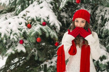 Noel ve yeni yıl kavramı. Kış vibes. Neşeli Noel ağacı yakınındaki eldiven ve kırmızı şapkalı kız. Uzay kopyalayın. portre