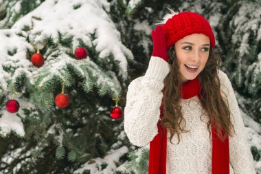 Noel ve yeni yıl kavramı. Kış vibes. Neşeli Noel ağacı yakınındaki eldiven ve kırmızı şapkalı kız. Uzay kopyalayın. portre