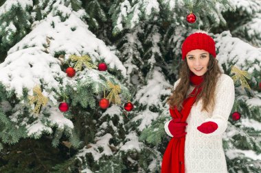 Noel ve yeni yıl kavramı. Kış vibes. Neşeli Noel ağacı yakınındaki eldiven ve kırmızı şapkalı kız. Uzay kopyalayın. portre