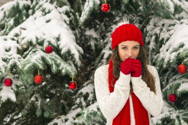 Noel ve yeni yıl kavramı. Kış vibes. Neşeli Noel ağacı yakınındaki eldiven ve kırmızı şapkalı kız. Uzay kopyalayın. portre