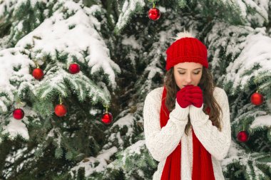 Noel ve yeni yıl kavramı. Kış vibes. Neşeli Noel ağacı yakınındaki eldiven ve kırmızı şapkalı kız. Uzay kopyalayın. portre