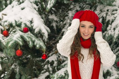 Noel ve yeni yıl kavramı. Kış vibes. Neşeli Noel ağacı yakınındaki eldiven ve kırmızı şapkalı kız. Uzay kopyalayın. portre