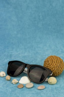 Kabukları ve bir top ip mavi bir arka plan üzerinde siyah güneş gözlüğü. Denizde, seyahat ve Cruise tatil kavramı