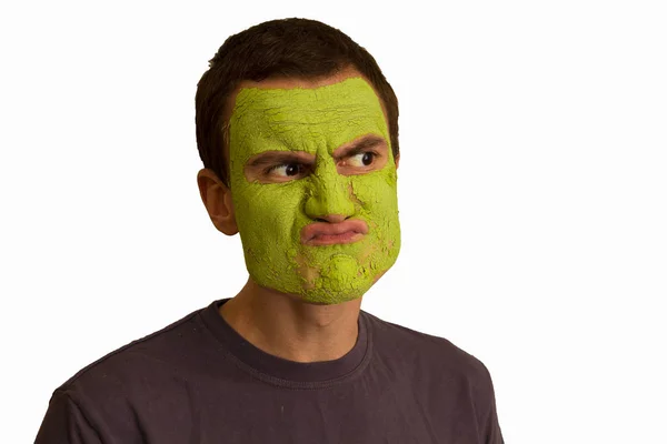 一个年轻的家伙的肖像与绿色的脸面具 使脸在白色的背景 面部化妆品的程序 — 图库照片