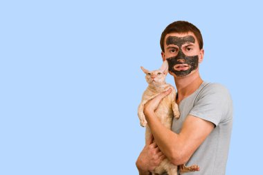 Mavi bir arka plan üzerinde siyah kozmetik maskeli adam. Yüz cilt bakımı. Yüz sorunları kavramı