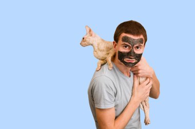 Mavi bir arka plan üzerinde siyah kozmetik maskeli adam. Yüz cilt bakımı. Yüz sorunları kavramı