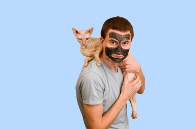 Mavi bir arka plan üzerinde siyah kozmetik maskeli adam. Yüz cilt bakımı. Yüz sorunları kavramı