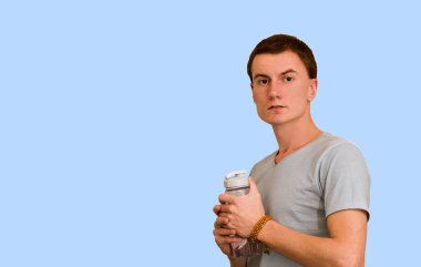 Adam bir şişe su mavi bir arka plan üzerinde tutar. Sağlıklı yaşam kavramı
