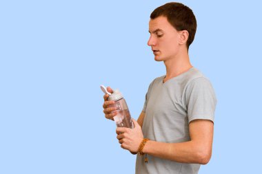 Adam bir şişe su mavi bir arka plan üzerinde tutar. Sağlıklı yaşam kavramı