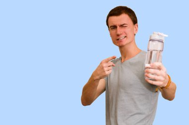 Adam bir şişe su mavi bir arka plan üzerinde tutar. Sağlıklı yaşam kavramı