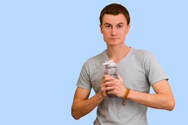 Adam bir şişe su mavi bir arka plan üzerinde tutar. Sağlıklı yaşam kavramı