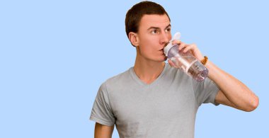 Adam bir şişe su mavi bir arka plan üzerinde tutar. Sağlıklı yaşam kavramı