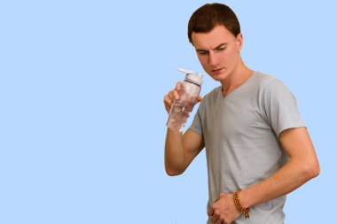 Adam bir şişe su mavi bir arka plan üzerinde tutar. Sağlıklı yaşam kavramı