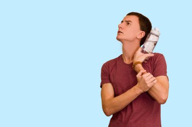 Adam bir şişe su mavi bir arka plan üzerinde tutar. Sağlıklı yaşam kavramı