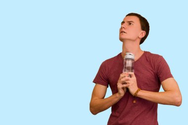 Adam bir şişe su mavi bir arka plan üzerinde tutar. Sağlıklı yaşam kavramı