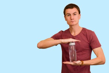 Adam bir şişe su mavi bir arka plan üzerinde tutar. Sağlıklı yaşam kavramı