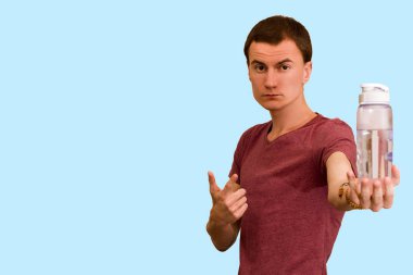 Adam bir şişe su mavi bir arka plan üzerinde tutar. Sağlıklı yaşam kavramı