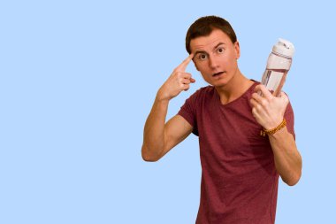 Adam bir şişe su mavi bir arka plan üzerinde tutar. Sağlıklı yaşam kavramı