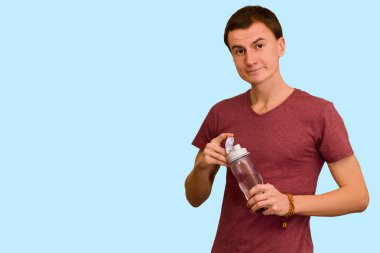 Adam bir şişe su mavi bir arka plan üzerinde tutar. Sağlıklı yaşam kavramı