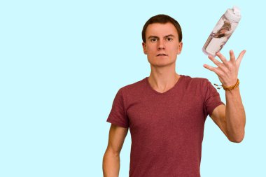 Adam bir şişe su mavi bir arka plan üzerinde tutar. Sağlıklı yaşam kavramı