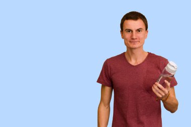 Adam bir şişe su mavi bir arka plan üzerinde tutar. Sağlıklı yaşam kavramı