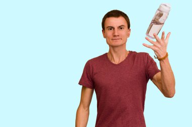 Adam bir şişe su mavi bir arka plan üzerinde tutar. Sağlıklı yaşam kavramı
