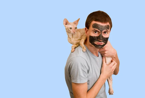 青の背景に黒化粧品マスクの男 顔のスキンケア 顔の美容トラブルの概念 — ストック写真