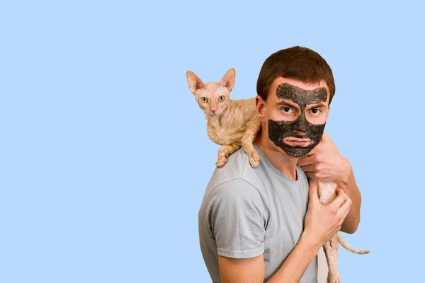 青の背景に黒化粧品マスクの男 顔のスキンケア 顔の美容トラブルの概念 — ストック写真