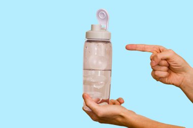 Şişe suyu mavi bir arka plan üzerinde bir elinde.