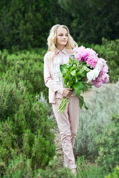 Beautiful girl with a big bouquet of peonies on her birthday.