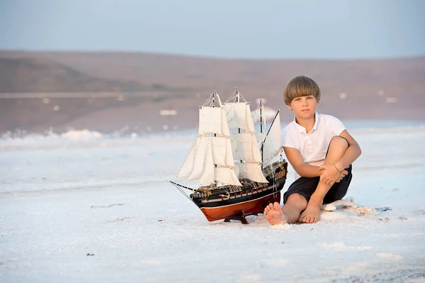 Boy with model ship on the salt lake and dreaming of becoming a captain