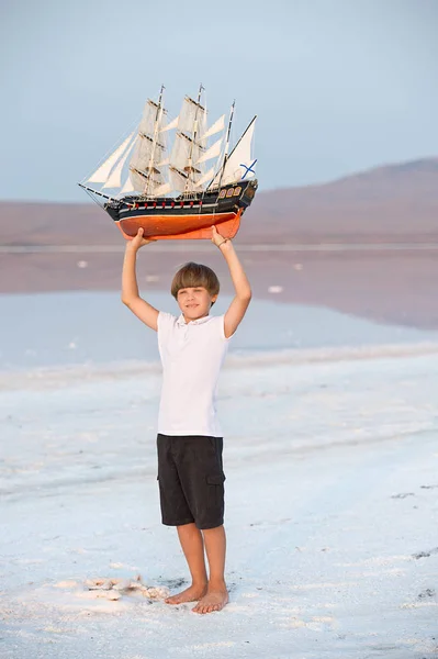 Boy holding model ship on the salt lake