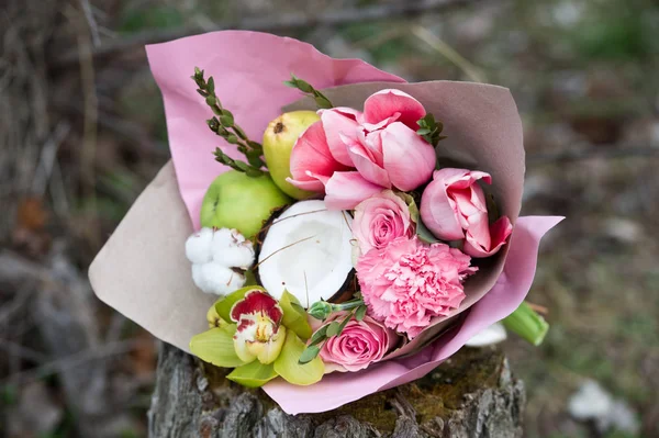 beautiful decorated bouquet of flowers and fruits on stump in forest