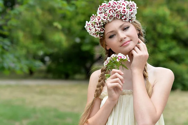 beautiful redhead girl with flower wreath in field