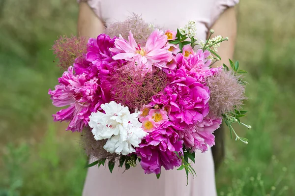 cropped shot of woman holding bouquet of peonies