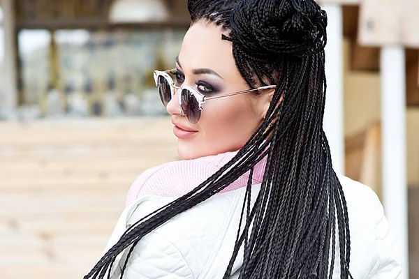 young woman in sun glasses with dreadlocks posing outdoor
