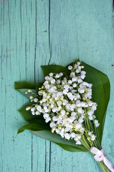 Spring bouquet of Lily of the valley on green wooden background. Decorative composition