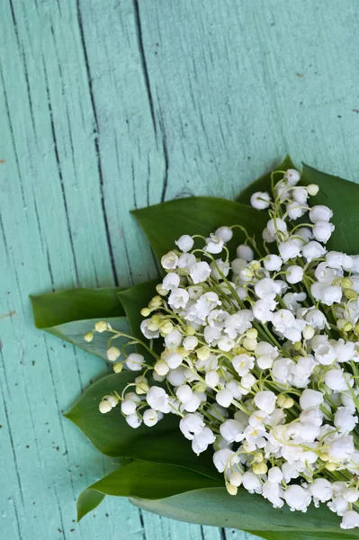 Spring bouquet of Lily of the valley on wooden background. Decorative composition