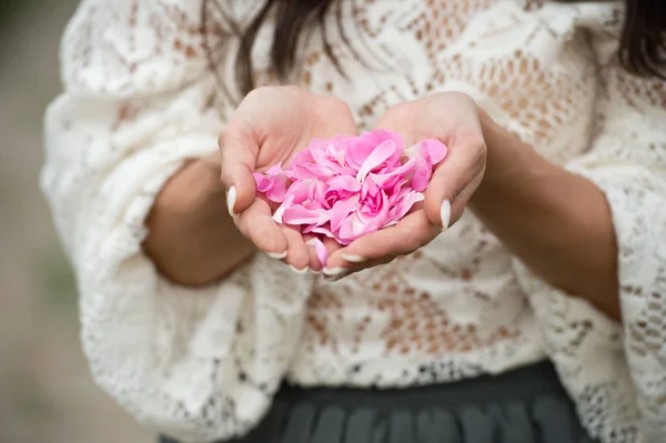 close up of woman holding rose flower petals in hands
