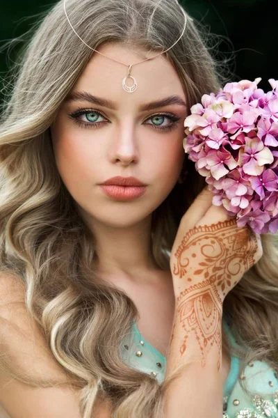 Beautiful young caucasian woman in traditional indian clothing with bridal makeup and jewelry. Gorgeous blonde bride. Mehndi, application of henna as skin decoration.